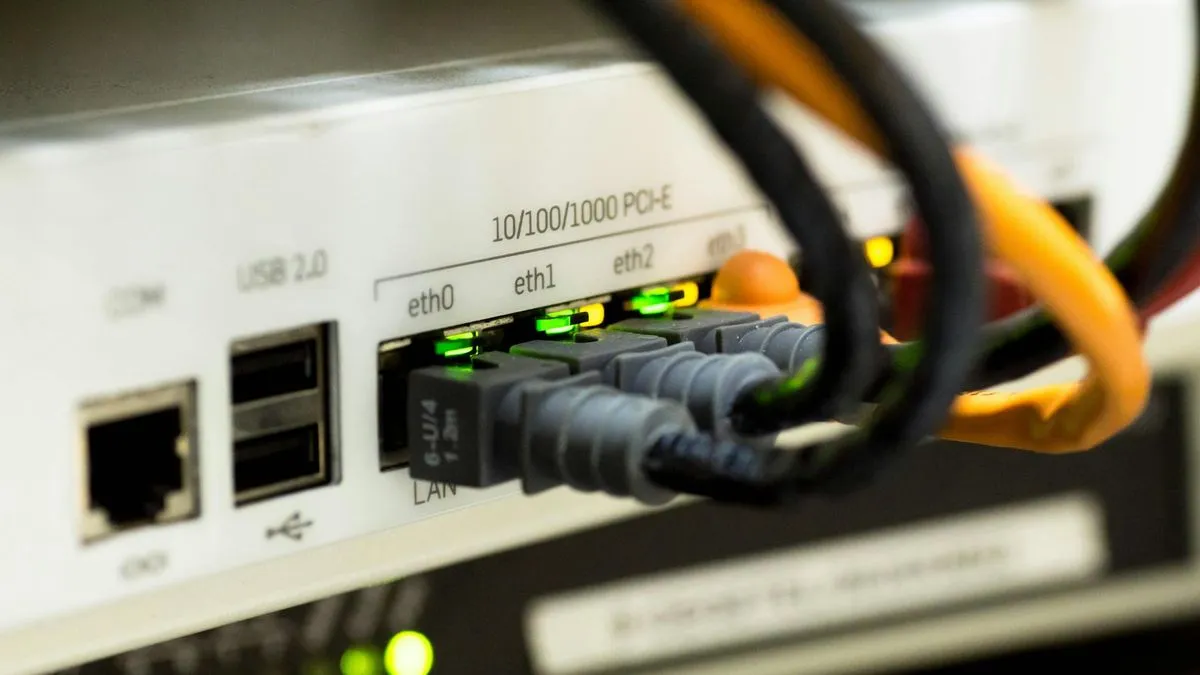 Close-up of a white router with several ethernet cables plugged into its ports, showing green indicator lights.