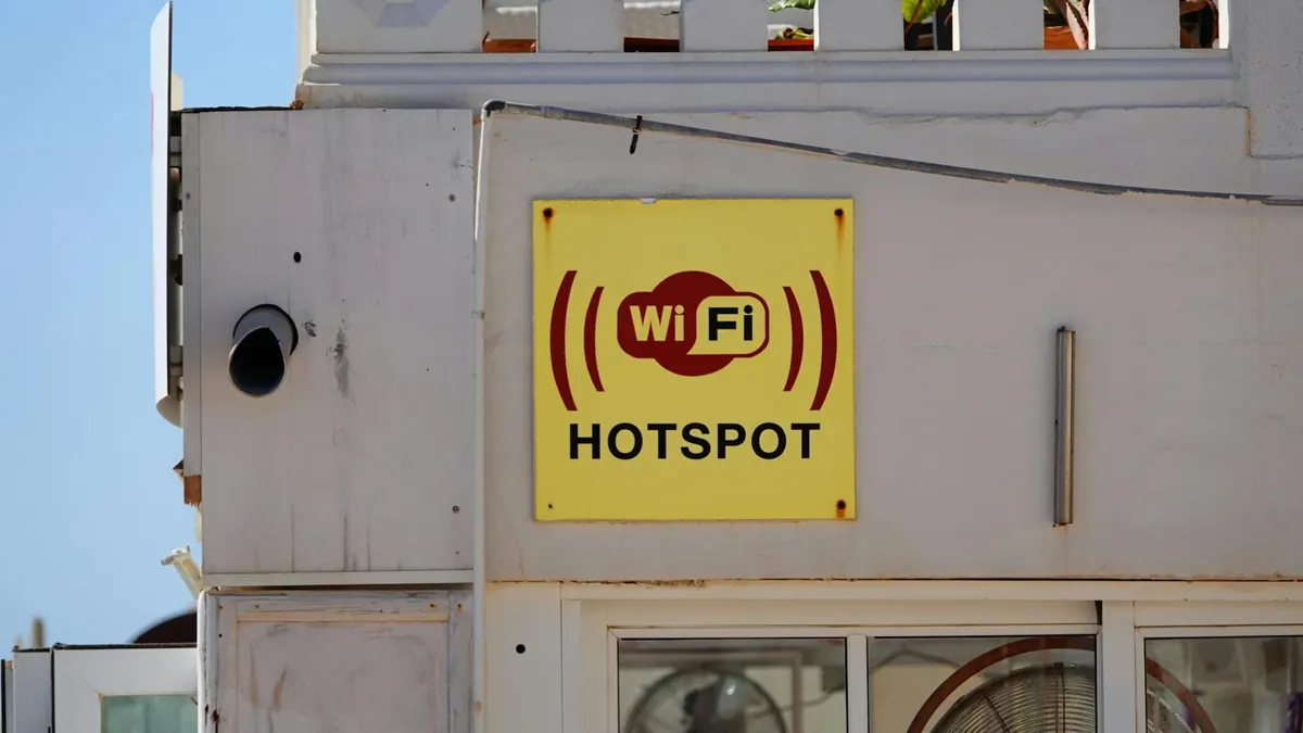 Yellow WiFi hotspot sign on a building facade in Cala Rajada, perfect for connectivity themes.