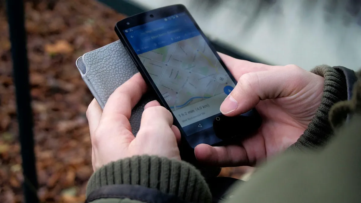 Close-up of hands using a map app on a smartphone outdoors, showcasing GPS navigation.