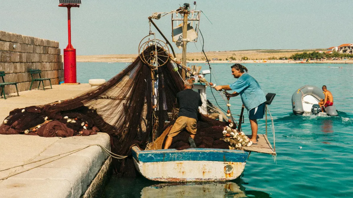 Fishermen pulling nets on a boat in the harbor of Zadar, Croatia, on a sunny day.