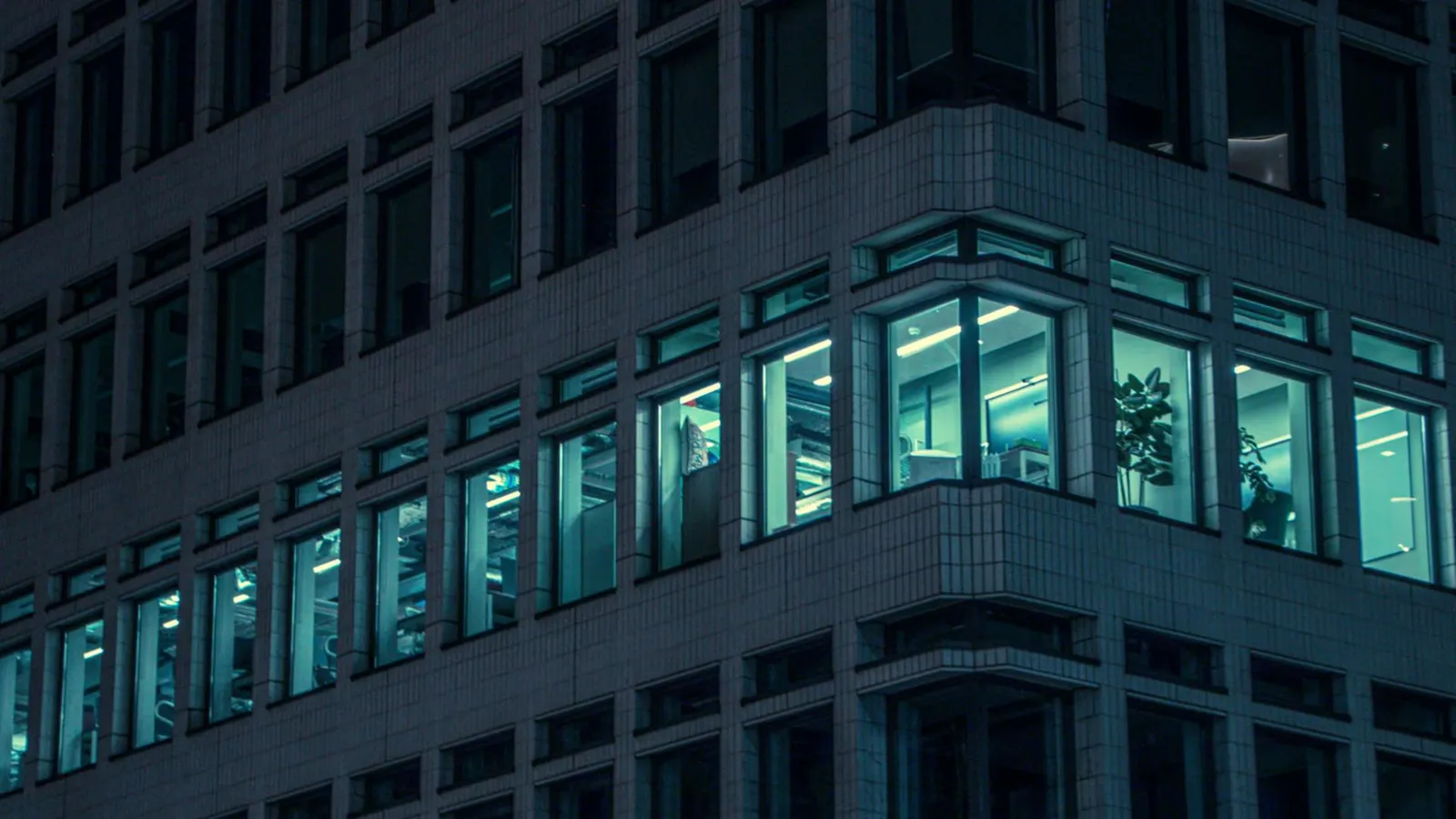 Illuminated office windows in a modern London building at night, capturing urban life.