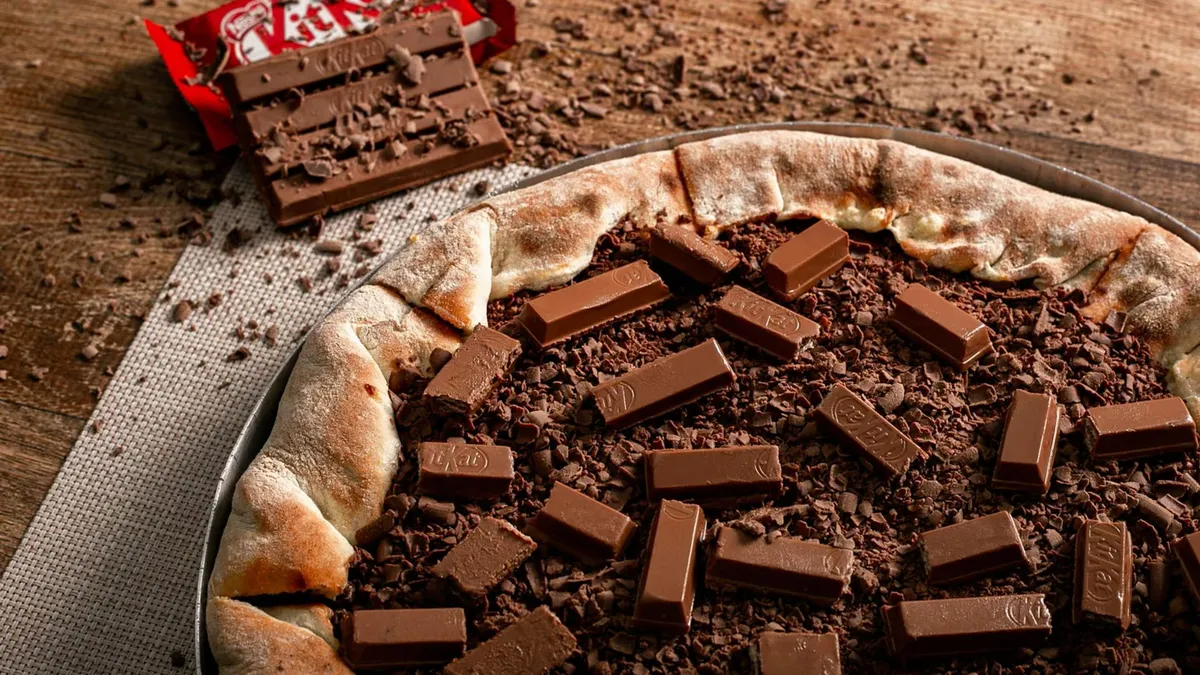 Mouth-watering chocolate pizza topped with KitKat bars, perfect for dessert lovers.