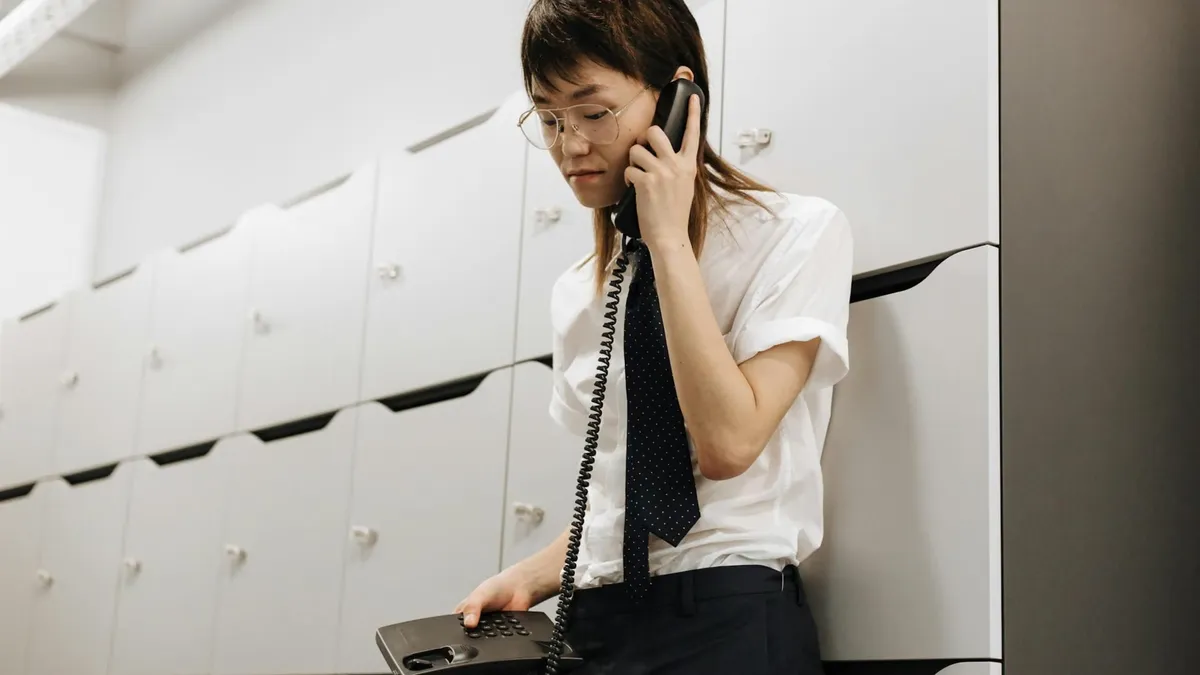 Asian male call center agent in office talking on phone, providing customer service.