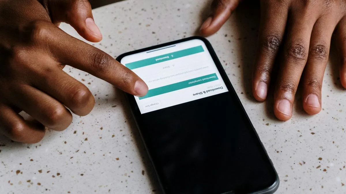 Close-up of hands interacting with a smartphone screen on a speckled white table.