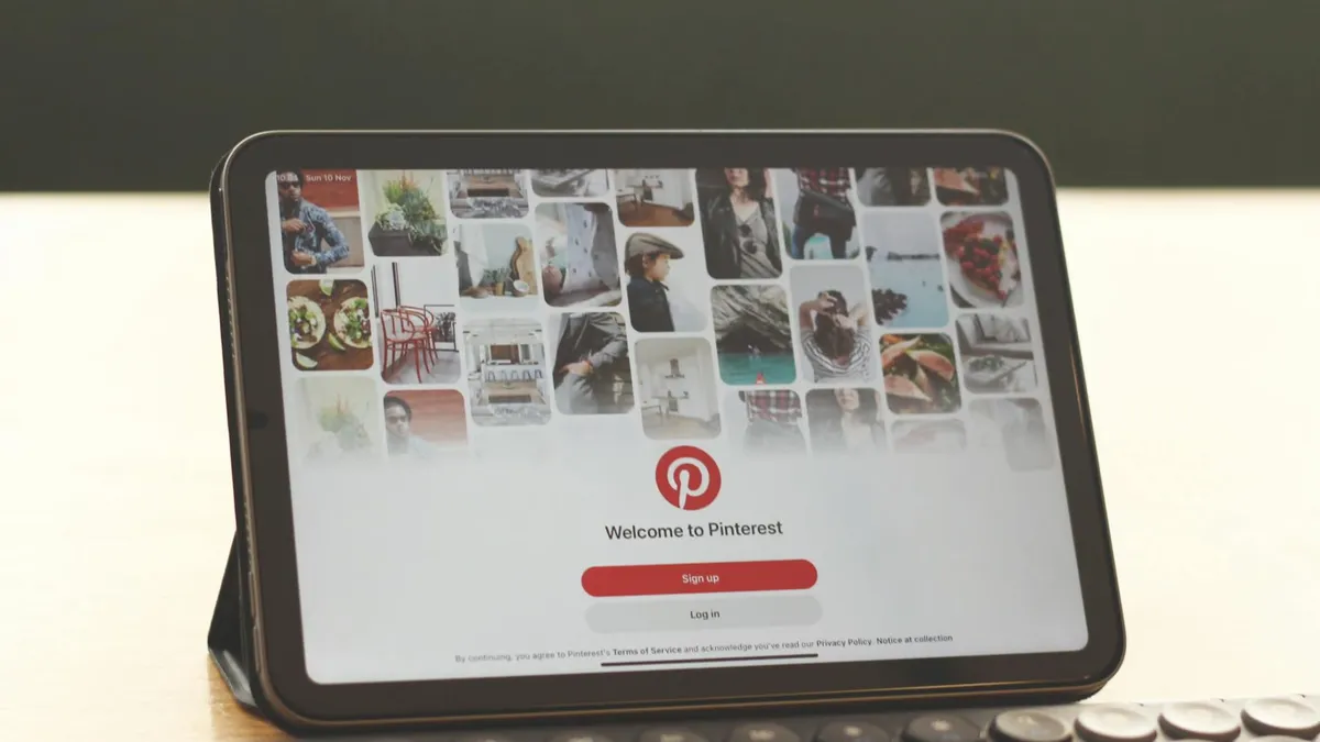 Tablet showing Pinterest homepage on a modern desk setup with a keyboard.
