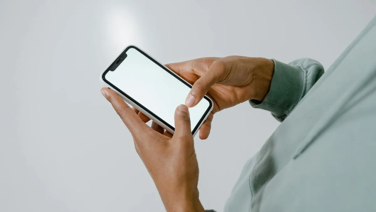 A person's hands holding a modern smartphone with a blank white screen, ready for interaction.