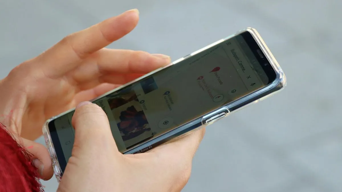 A person's hands holding a smartphone with a screen displaying an application.