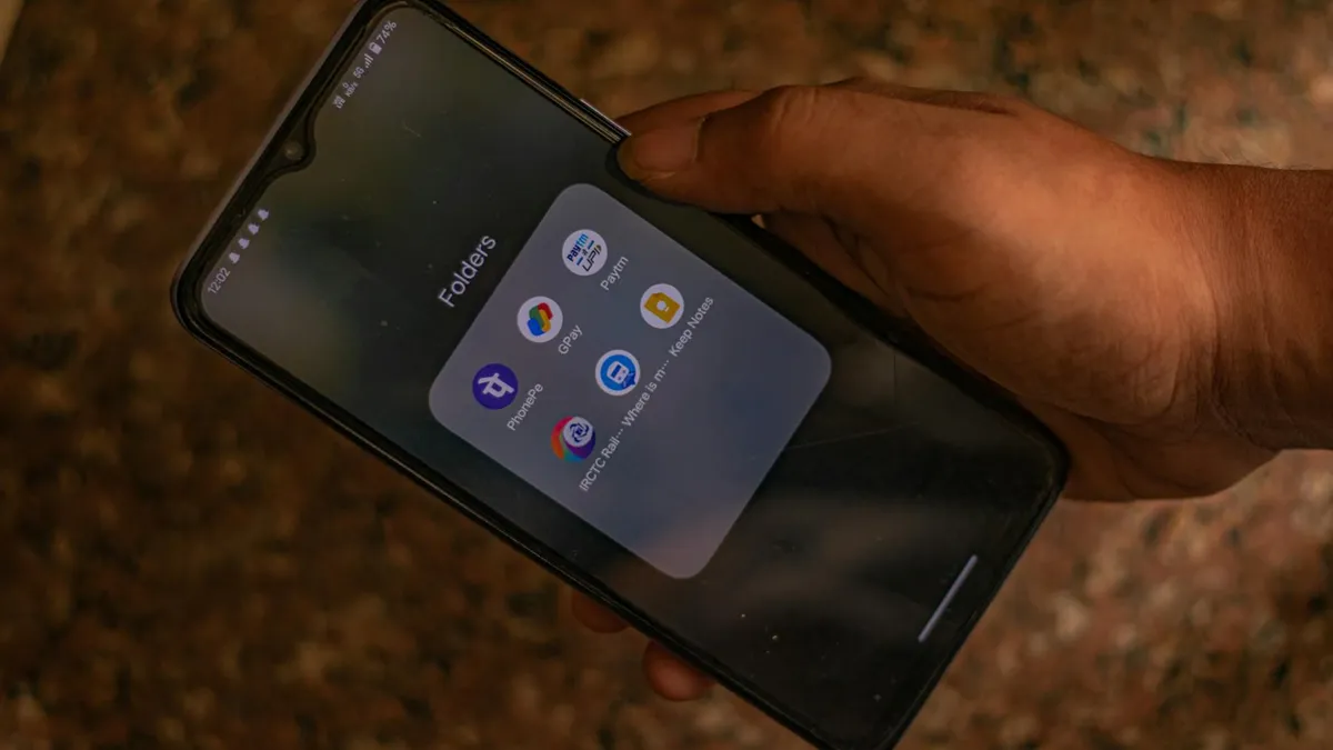 A hand holds a smartphone displaying popular payment apps for digital transactions.