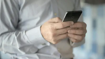 Close-up of a businessman using a smartphone, highlighting business and communication themes.