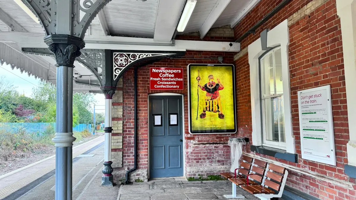A vintage train platform with a colorful poster and classic architecture in the UK.