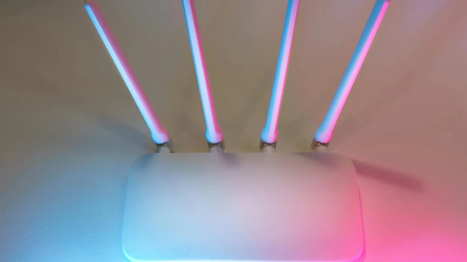 Sleek white wireless router with four antennas emitting soft blue and pink light.