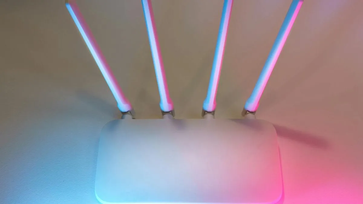 A white broadband router with four antennas, illuminated by blue and pink neon lights.