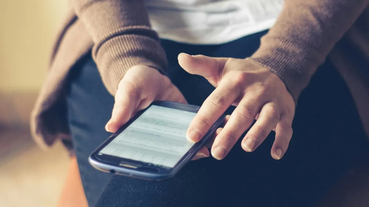 Close-up of adult using smartphone indoors, browsing web with focus on screen.