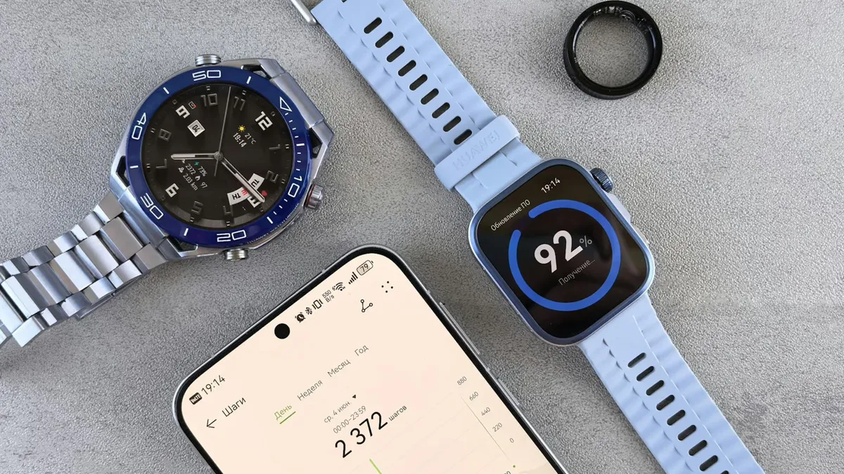 Smartwatch, ring tracker, and smartphone displaying fitness data on a gray surface.