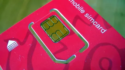 Close-up of a SIM card being held, showing the microchip and gold contacts used for mobile activation.