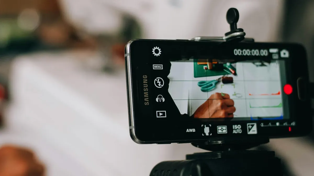 Smartphone on tripod capturing person writing on paper, showing content creation process.