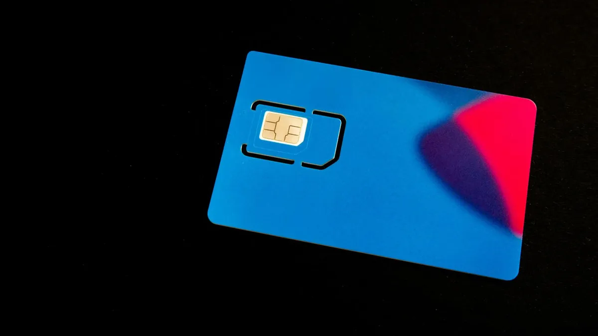 A blue SIM card on a dark background with vibrant red and purple accents.