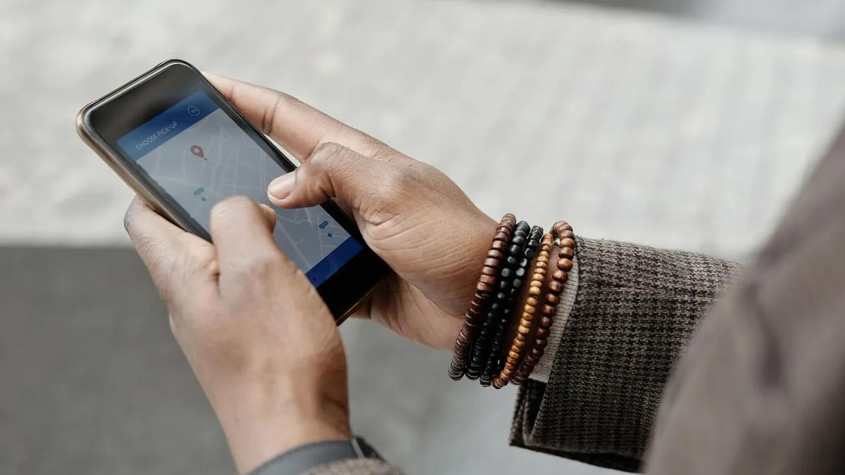 A person's hands holding a smartphone displaying a map application with a red pin.