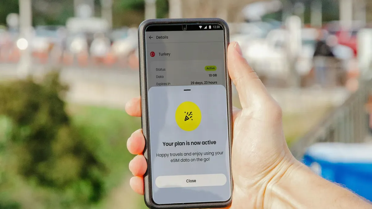 Smartphone showing active eSIM plan held outdoors, blurred city background.