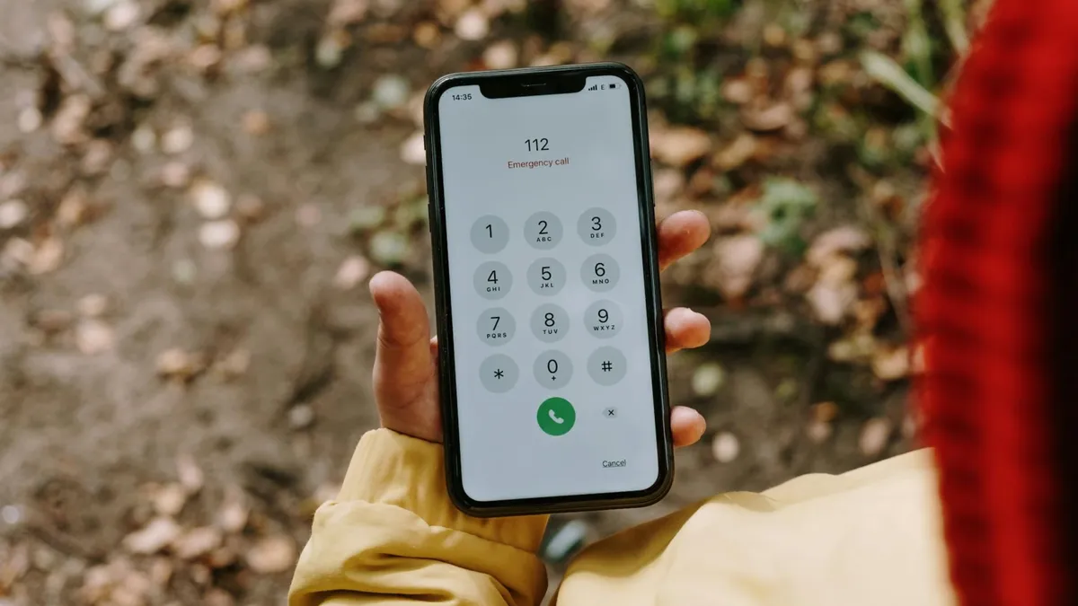 Close-up of a smartphone displaying emergency number 112 outdoors.