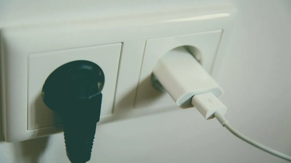 A white wall socket with a black plug and a white USB charger plugged in.