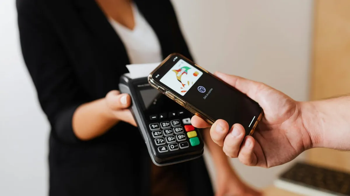 A person using a smartphone for contactless payment at a retail store counter.
