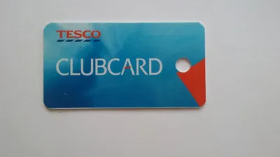 Customer holding Tesco shopping bags at a supermarket checkout