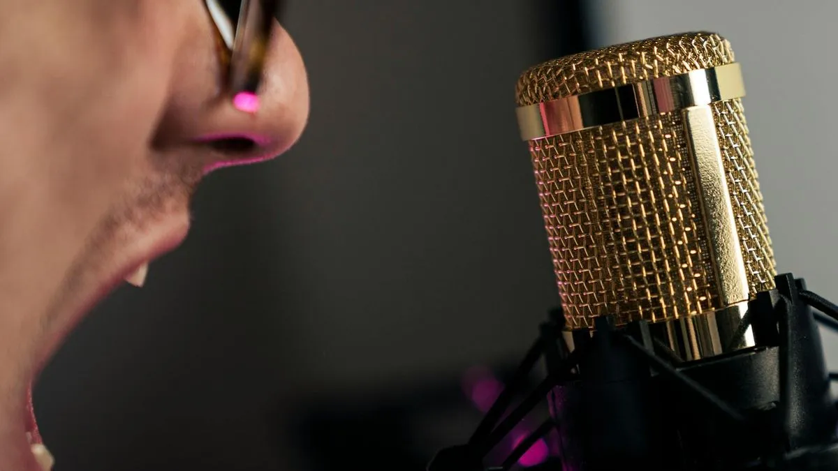 Close-up of a person's mouth speaking into a gold-colored studio microphone.