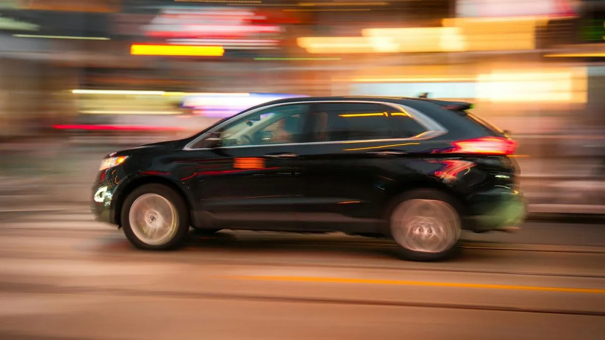 A black SUV with blurred background lights, suggesting motion and speed on a city street.