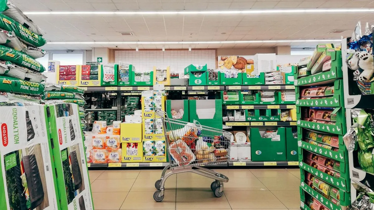 A shopping cart filled with groceries in the middle of a supermarket aisle.