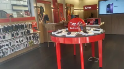 Interior of a Vodafone mobile phone retail store with display counters and signage