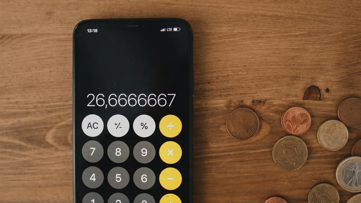 Close-up view of smartphone calculator and coins on wooden surface for financial metaphor.