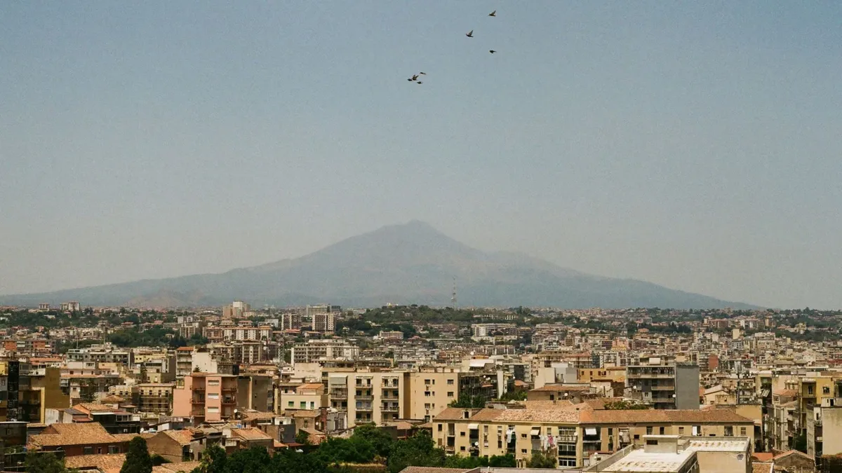 Aerial panorama of Catania, Sicily with distant Mount Etna under a clear sky.