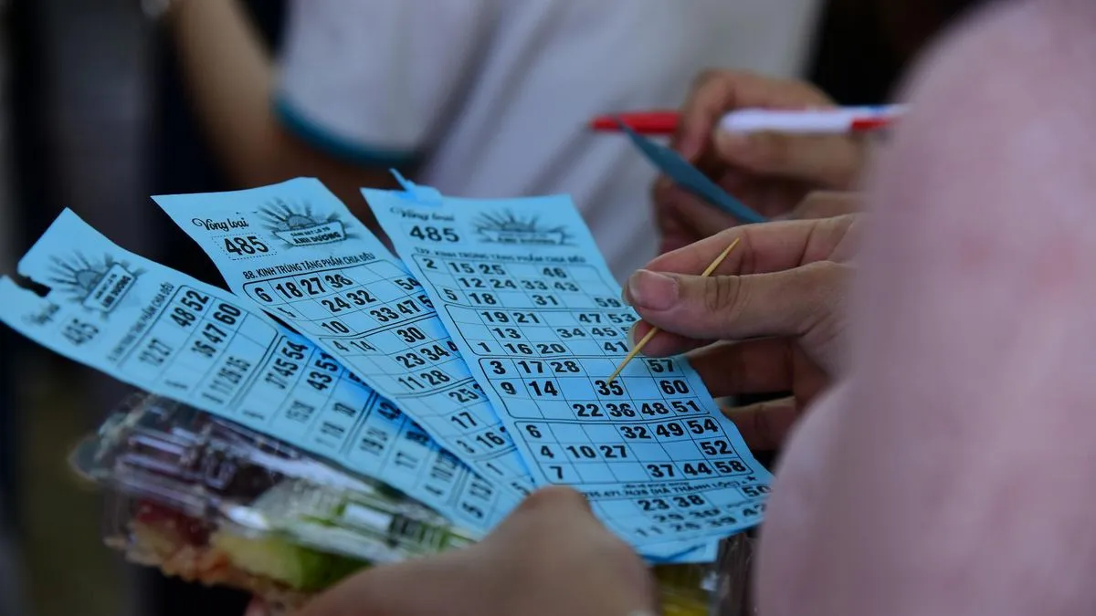 Close-up of hands holding and marking blue bingo cards with a toothpick.