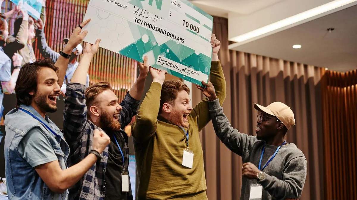 Four men celebrating with a large novelty check for ten thousand dollars, one man holding it up.