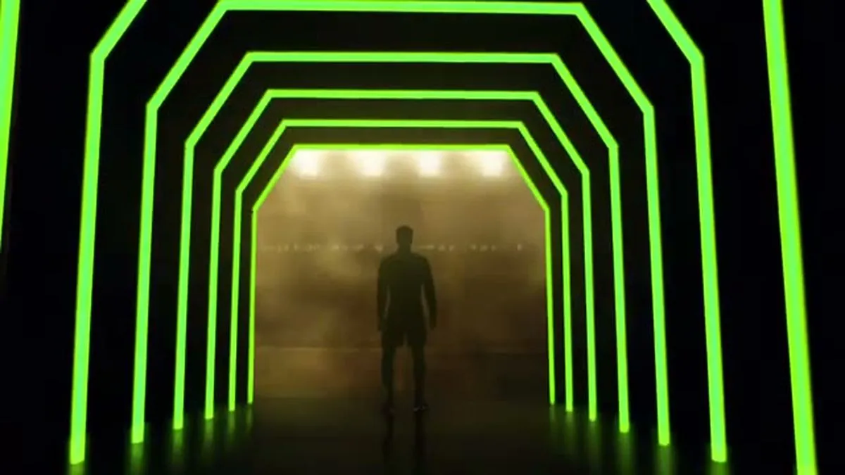 A silhouette of Raheem Sterling stands at the end of a neon green tunnel, looking towards a bright stadium.