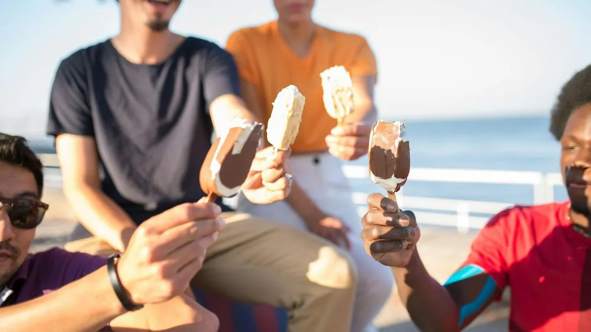 Four diverse people holding up Magnum-like ice cream bars towards the camera.