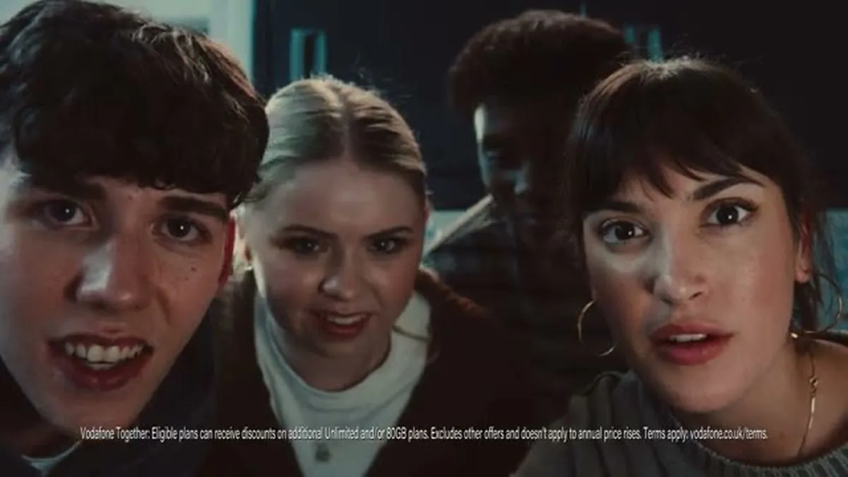 Four young adults look intently at something off-screen, with surprised expressions.