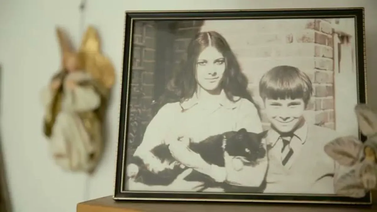 A framed black and white photo of a young woman holding a cat and a young boy smiling.
