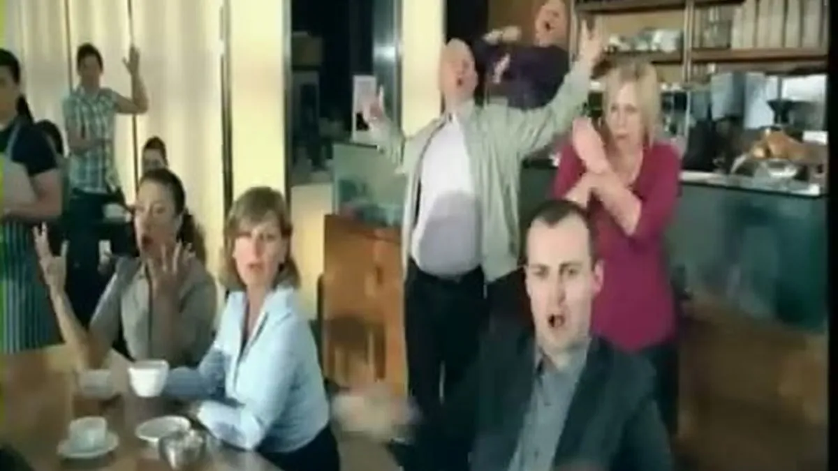 Several people in a coffee shop react with exaggerated gestures and open mouths, looking surprised or annoyed.